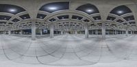 a fisheye photo is seen of a street with arches and pillars above them and a person standing on a sidewalk