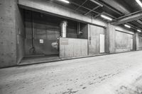 black and white photo of open building door with no doors and exposed ceilings and a long empty floor