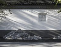 stone statues on either side of the walkway in a garden of trees and shrubs with white wall