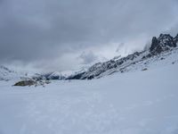 a man that is skiing across some snow covered mountains by trees and rocks in the distance