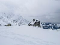 a view of a snowy landscape and mountains from atop a mountain peak with some wires