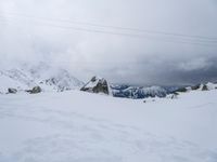 a view of a snowy landscape and mountains from atop a mountain peak with some wires