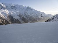 a person riding skis down a snow covered slope next to a mountain in the evening