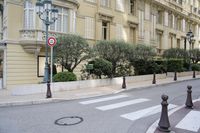 an empty city street in a large european city with multiple tall buildings and bushes around