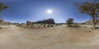 a 360 - view photo of a dirt road in the desert with a sun above the road