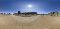 a 360 - view image with sand and rocks in the background, and sun behind them