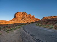 a desert road with desert and mountains in the background at sunset and sun setting on top