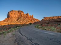 a desert road with desert and mountains in the background at sunset and sun setting on top