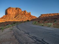 a desert road with desert and mountains in the background at sunset and sun setting on top