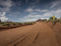 a dirt road with signs on each side of it surrounded by red rocks and cactus