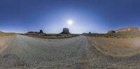 360 - view photograph of a desert in the background, and a large rock formation with a sun over it