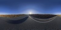 a car is parked on an empty roadway in front of the sun and blue sky