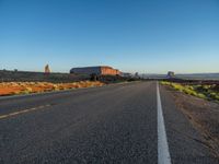 an empty, open road stretches from the mountains to the horizon in the desert during sunset