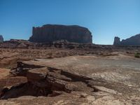 large expanse of rock formations at the base of an area of desert terrain with sparse plants and dirt