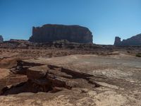 large expanse of rock formations at the base of an area of desert terrain with sparse plants and dirt