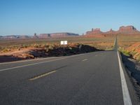 an empty road near some rocky mountains in the desert on a clear day with blue skies