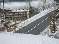 a view of a town across the water and mountains in winter time with a road going to the right
