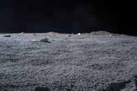 rocks sit alone on top of some grass on the surface of space, lit by spotlight from bright spotlights