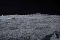 rocks sit alone on top of some grass on the surface of space, lit by spotlight from bright spotlights