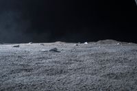 rocks sit alone on top of some grass on the surface of space, lit by spotlight from bright spotlights