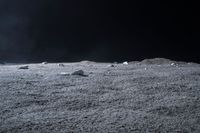 rocks sit alone on top of some grass on the surface of space, lit by spotlight from bright spotlights