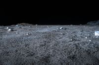 a view of rock and boulders on a dark moon surface, taken from a low angle