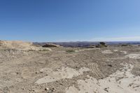 a large rock in a barren area with clear blue skies on a sunny day,