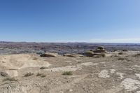 a large rock in a barren area with clear blue skies on a sunny day,