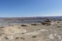 a large rock in a barren area with clear blue skies on a sunny day,