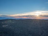 the sun shines on an empty rocky road in iceland, where the beach is next to the water