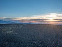 the sun shines on an empty rocky road in iceland, where the beach is next to the water