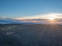 the sun shines on an empty rocky road in iceland, where the beach is next to the water