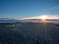 the sun shines on an empty rocky road in iceland, where the beach is next to the water