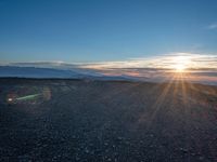 the sun shines on an empty rocky road in iceland, where the beach is next to the water