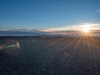 the sun shines on an empty rocky road in iceland, where the beach is next to the water