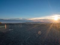 the sun shines on an empty rocky road in iceland, where the beach is next to the water