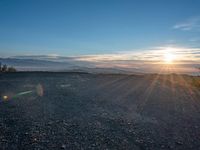 the sun shines on an empty rocky road in iceland, where the beach is next to the water