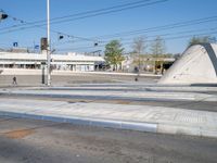 a man is crossing an empty street in the morning with a skateboard on the ground