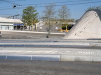 a man is crossing an empty street in the morning with a skateboard on the ground