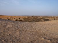 a truck on a dirt road in the desert with rocks and stones on the ground