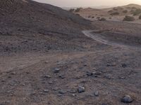 a truck on a dirt road in the desert with rocks and stones on the ground