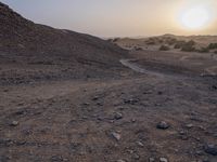 a truck on a dirt road in the desert with rocks and stones on the ground