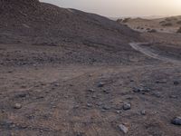 a truck on a dirt road in the desert with rocks and stones on the ground