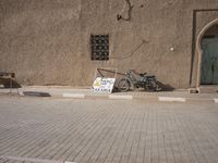 a small bike is parked on the pavement in front of a small building that has a sign about what to do