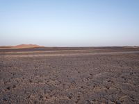 the barren desert landscape is in the morning sun light with a few clouds overhead it