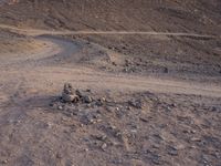 a truck on a dirt road in the desert with rocks and stones on the ground