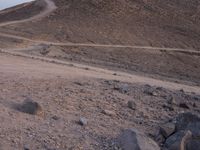 a truck on a dirt road in the desert with rocks and stones on the ground