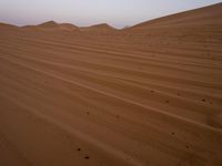 a desert with small mounds in the middle of it, with sparse soil and small dots