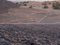 a truck on a dirt road in the desert with rocks and stones on the ground