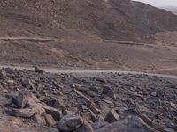 a truck on a dirt road in the desert with rocks and stones on the ground